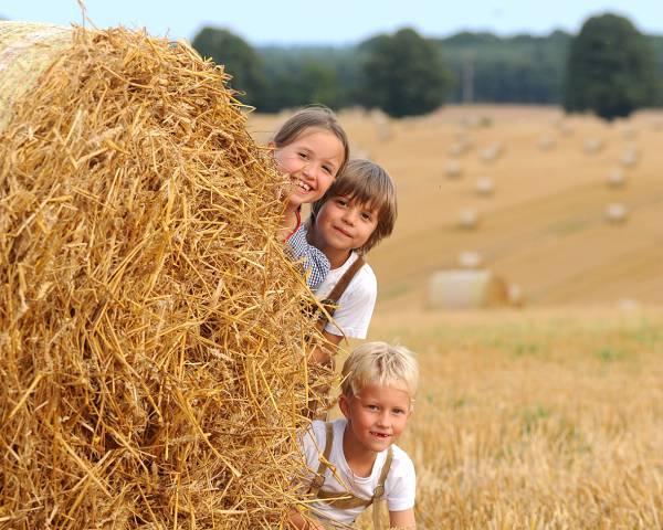 Kinder spielen hinter einem Heuballen