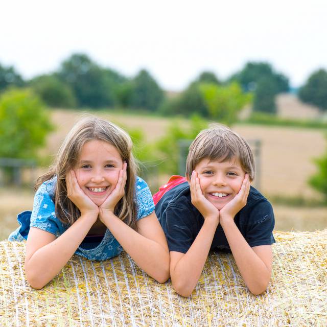 Zwei Kinder liegen auf Heuballen