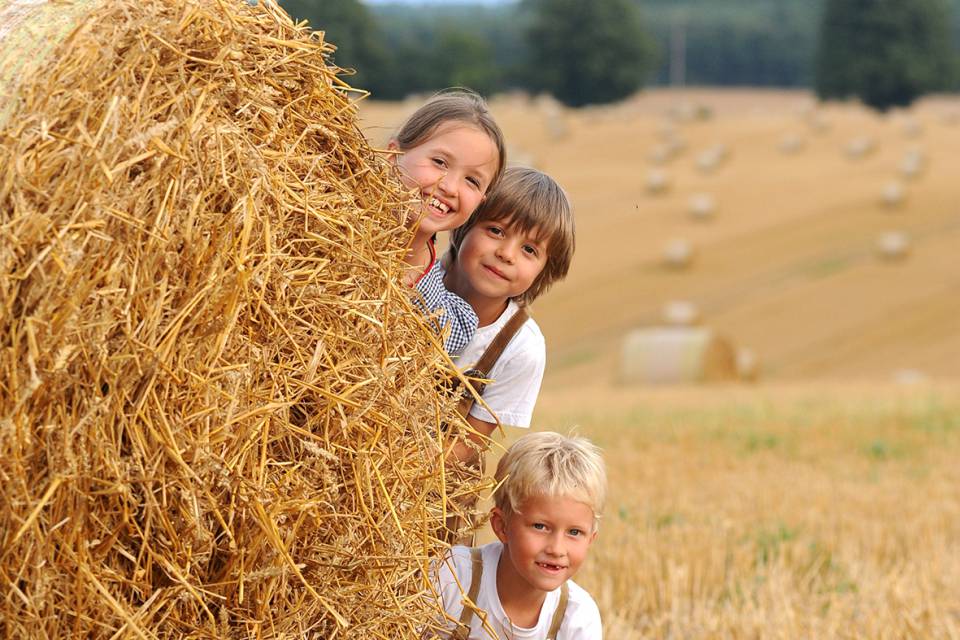 Kinder spielen hinter einem Heuballen