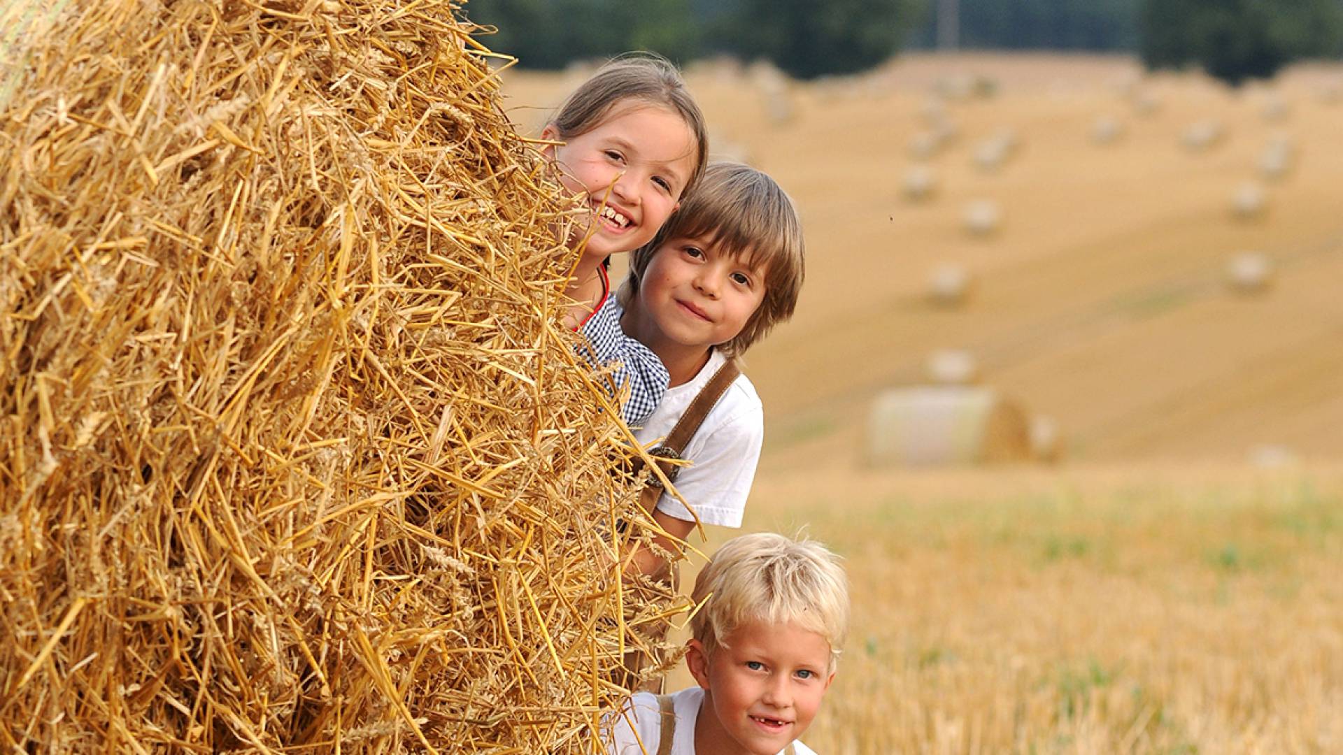 Kinder spielen hinter einem Heuballen