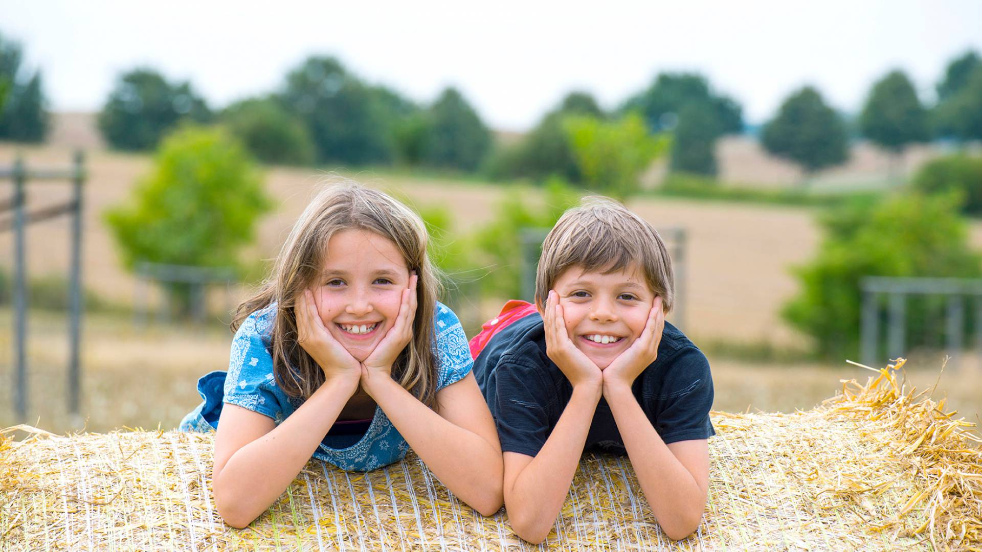 Zwei Kinder liegen auf Heuballen