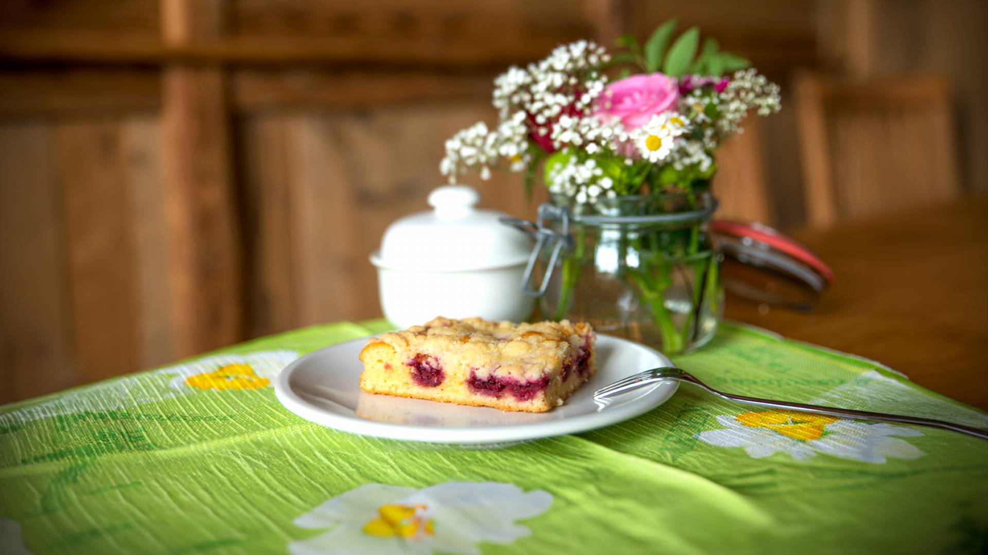 Gedeckter Tisch mit Kuchen und Blumen
